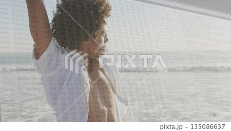 Stretching man in white shirt raising arms at sandy shore left, binary code overlay, copy space 135086637