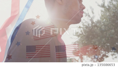 Standing man in sunlight outside, with red blue streamers, flag and star overlays, copy space 135086653