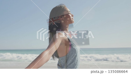 Standing woman stretching arms toward sun on sandy beach, wearing sportswear, copy space 135086664