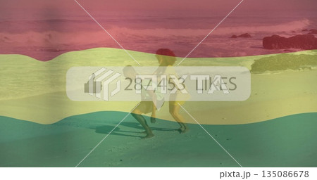 Friends dancing holding smartphone in ocean waves at rocky beach, with likes overlay under pink sky 135086678