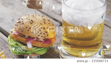 Displaying seeded slider burger and glass beer mug on rustic patio table, with social media icons 135086715