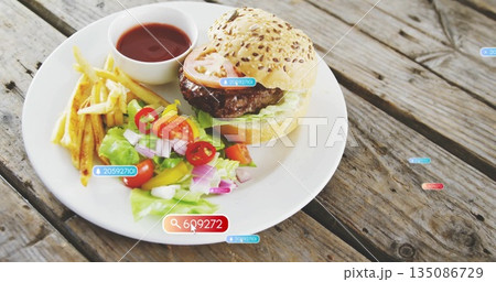 Displaying plate holding seeded burger with lettuce tomato, fries, salad and ketchup on wood table 135086729