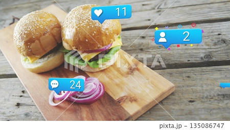 Displaying sesame seed burgers with lettuce and cheese resting on board, with social icons 135086747