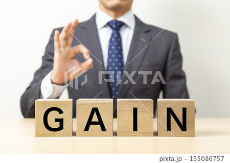 「GAIN」と書かれたブロックとOKポーズをするビジネスマン 135086757