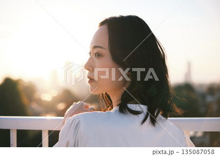 夕暮れ 屋上にいる女性のポートレート 135087058