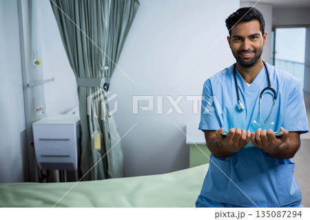 Asian male in scrubs with stethoscope using smartphone by hospital bed, privacy curtain, copy space 135087294