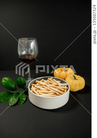 Crispy small breadsticks served on a white glass plate against a black background. Minimalistic food composition highlighting texture, contrast, and simple snack presentation. 135087324