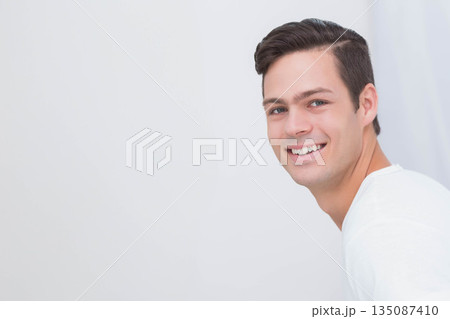 Man smiling and looking over left shoulder in studio with white backdrop, copy space 135087410