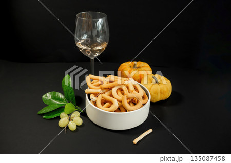 Crispy small breadsticks served on a white glass plate against a black background. Minimalistic food composition highlighting texture, contrast, and simple snack presentation. Crispy small breadsticks served on a white glass plate against a black background. Minimalistic food composition highlighting texture, contrast, and simple snack presentation. 135087458