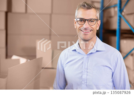 Man standing in warehouse storage area wearing smart glasses and inspecting boxes, copy space 135087926