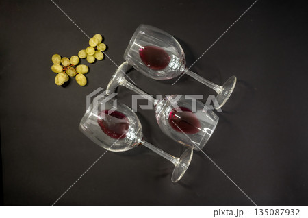 Elegant row of three empty wine glasses on a black background. Minimalistic, reflective glassware composition with clean lines and moody lighting. Perfect for wine, bar, and restaurant concepts. 135087932
