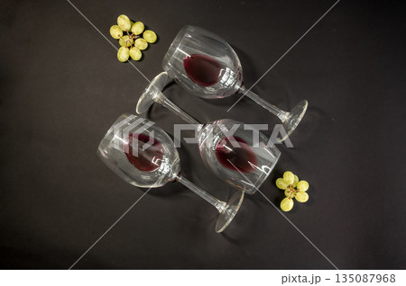 Elegant row of three empty wine glasses on a black background. Minimalistic, reflective glassware composition with clean lines and moody lighting. Perfect for wine, bar, and restaurant concepts. Elegant row of three empty wine glasses on a black background. Minimalistic, reflective glassware composition with clean lines and moody lighting. Perfect for wine, bar, and restaurant concepts. 135087968