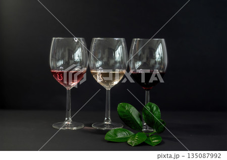 Elegant row of three empty wine glasses on a black background. Minimalistic, reflective glassware composition with clean lines and moody lighting. Perfect for wine, bar, and restaurant concepts. Elegant row of three empty wine glasses on a black background. Minimalistic, reflective glassware composition with clean lines and moody lighting. Perfect for wine, bar, and restaurant concepts. 135087992