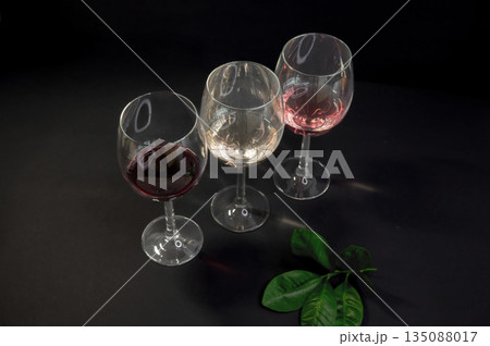 Elegant row of three empty wine glasses on a black background. Minimalistic, reflective glassware composition with clean lines and moody lighting. Perfect for wine, bar, and restaurant concepts. 135088017