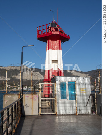 August 22 2025 Entrance lighthouse of Novorossiysk port Russia red and white on the Black Sea coast. Maritime navigation aid near the harbor 135088652
