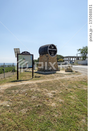 August 24, 2025: Genre sculpture of a barrel with winery sign in Myskhako, Russia, with the sea and mountains on the horizon, symbolizing local winemaking, tourism and coastal landscape 135088831