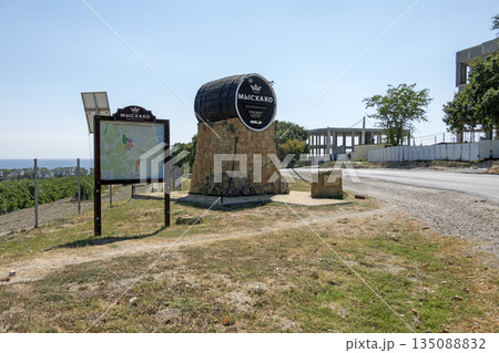 August 24, 2025: Genre sculpture of a barrel with winery sign in Myskhako, Russia, with the sea and mountains on the horizon, symbolizing local winemaking, tourism and coastal landscape 135088832