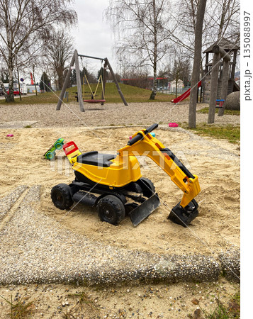 Large yellow toy excavator in a playground sandpit Large yellow toy excavator in a playground sandpit 135088997