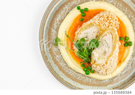 Breaded chicken roulade with mashed potatoes, carrot puree, green peas, and microgreens on a ceramic plate. copy space, top view Breaded chicken roulade with mashed potatoes, carrot puree, green peas, and microgreens on a ceramic plate. copy space, top view 135089384