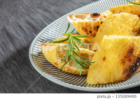 crispy focaccia bread slices with rosemary on a plate close up. top view crispy focaccia bread slices with rosemary on a plate close up. top view 135089400