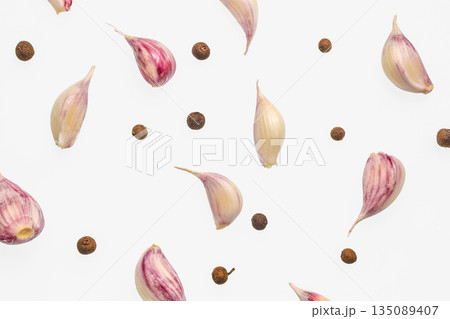 Garlic cloves and peppercorns scattered on white background, top view Garlic cloves and peppercorns scattered on white background, top view 135089407