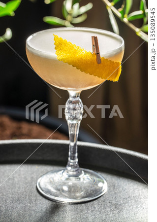 Elegant cocktail in a crystal coupe glass with lemon zest garnish in natural sunlight Elegant cocktail in a crystal coupe glass with lemon zest garnish in natural sunlight 135089545