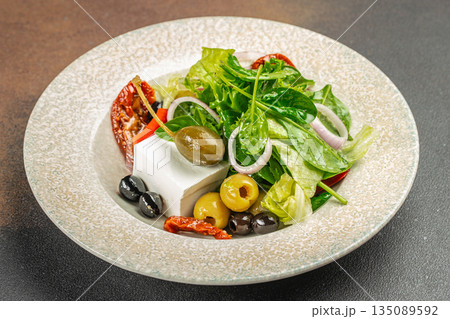 Greek salad with feta cheese, olives, and fresh vegetables on a plate Greek salad with feta cheese, olives, and fresh vegetables on a plate 135089592