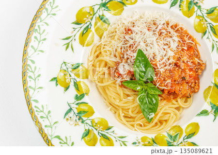 Spaghetti with bolognese sauce and parmesan cheese on a decorated plate. top view 135089621