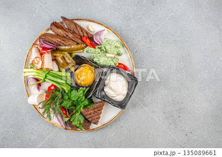 Traditional assorted snack platter with rye bread, pickles, mustard, creamy dips, herbs, onion, garlic, and spiced meat slices 135089661