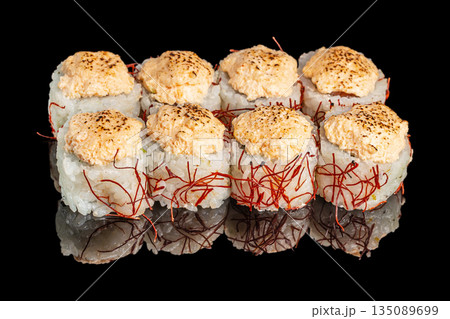 Sushi rolls topped with a torched spicy creamy mixture and wrapped in rice with decorative red threads are artfully presented on a reflective black surface Sushi rolls topped with a torched spicy creamy mixture and wrapped in rice with decorative red threads are artfully presented on a reflective black surface 135089699