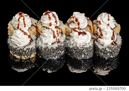 Decorative sushi rolls topped with swirls of creamy sauce and drizzled with soy glaze are beautifully coated in black and white sesame seeds 135089700