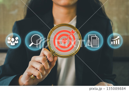 Businesswoman using magnifying glass with target icon, symbolizing focus on business strategy, goals, and success. Businesswoman using magnifying glass with target icon, symbolizing focus on business strategy, goals, and success. 135089884