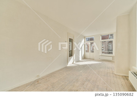A bright, spacious room featuring large windows that allow abundant natural light. The area has a minimalistic design with light-colored walls and wooden flooring. A bright, spacious room featuring large windows that allow abundant natural light. The area has a minimalistic design with light-colored walls and wooden flooring. 135090682