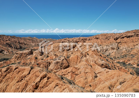 Layered clay sandstone hills and valleys in a desolate landscape with blue sky Layered clay sandstone hills and valleys in a desolate landscape with blue sky 135090783