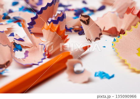 Orange pencil tip surrounded by colorful wood shavings on a white background Orange pencil tip surrounded by colorful wood shavings on a white background 135090966