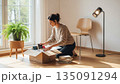 明るい白い部屋で段ボールを開ける新生活の女性 135091294