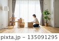 明るい白い部屋で段ボールを開ける新生活の女性 135091295