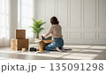 明るい白い部屋で段ボールを開ける新生活の女性 135091298