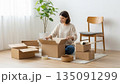 明るい白い部屋で段ボールを開ける新生活の女性 135091299