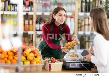 Young saleswoman giving bananas in grocery store 135091320