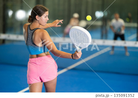 Young woman playing tennis against man and woman 135091352