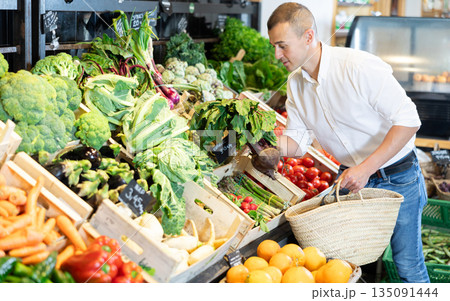 In vegetable department of bio supermarket, male customer took bunch of beets from window 135091444
