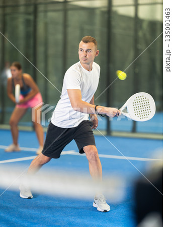 Young woman and man playing doubles tennis 135091463