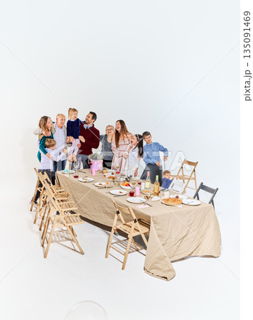 Warm multigenerational family gathering around festive dinner table. Warm multigenerational family gathering around festive dinner table. 135091469