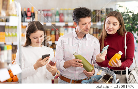Family of buyers scans QR code on smoothie fruit mix cocktail packaging 135091470