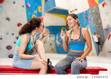 Young and middle-aged women talking merrily sitting in climbing hangar Young and middle-aged women talking merrily sitting in climbing hangar 135091472