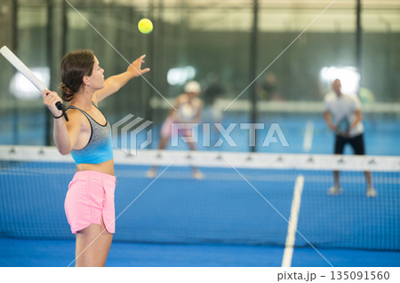 Young woman playing tennis against man and woman Young woman playing tennis against man and woman 135091560