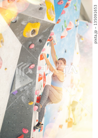 Woman in sportswear practicing rock climbing on climbing wall Woman in sportswear practicing rock climbing on climbing wall 135091653