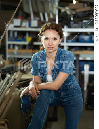 Portrait of confident female worker in workshop of metallurgical plant Portrait of confident female worker in workshop of metallurgical plant 135091697