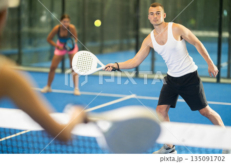 Young woman and man playing tennis against woman 135091702